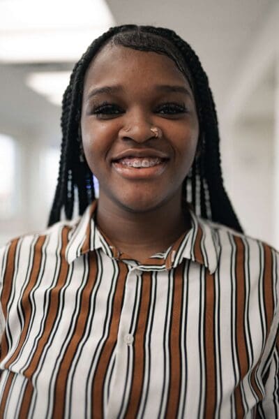 Smiling teen with metal braces and nose ring in striped shirt at Ruco Braces Smyrna TN orthodontic office
