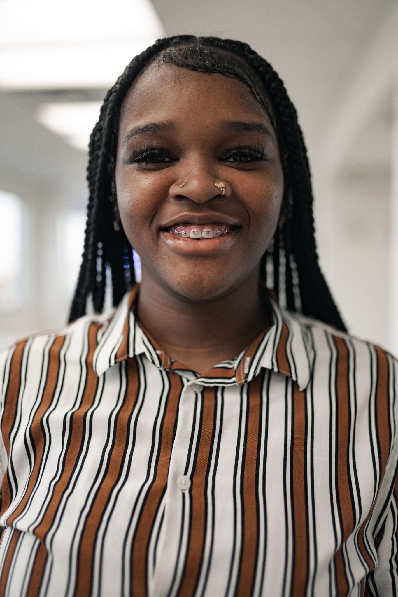 Smiling teen with metal braces and nose ring in striped shirt at Ruco Braces Smyrna TN orthodontic office